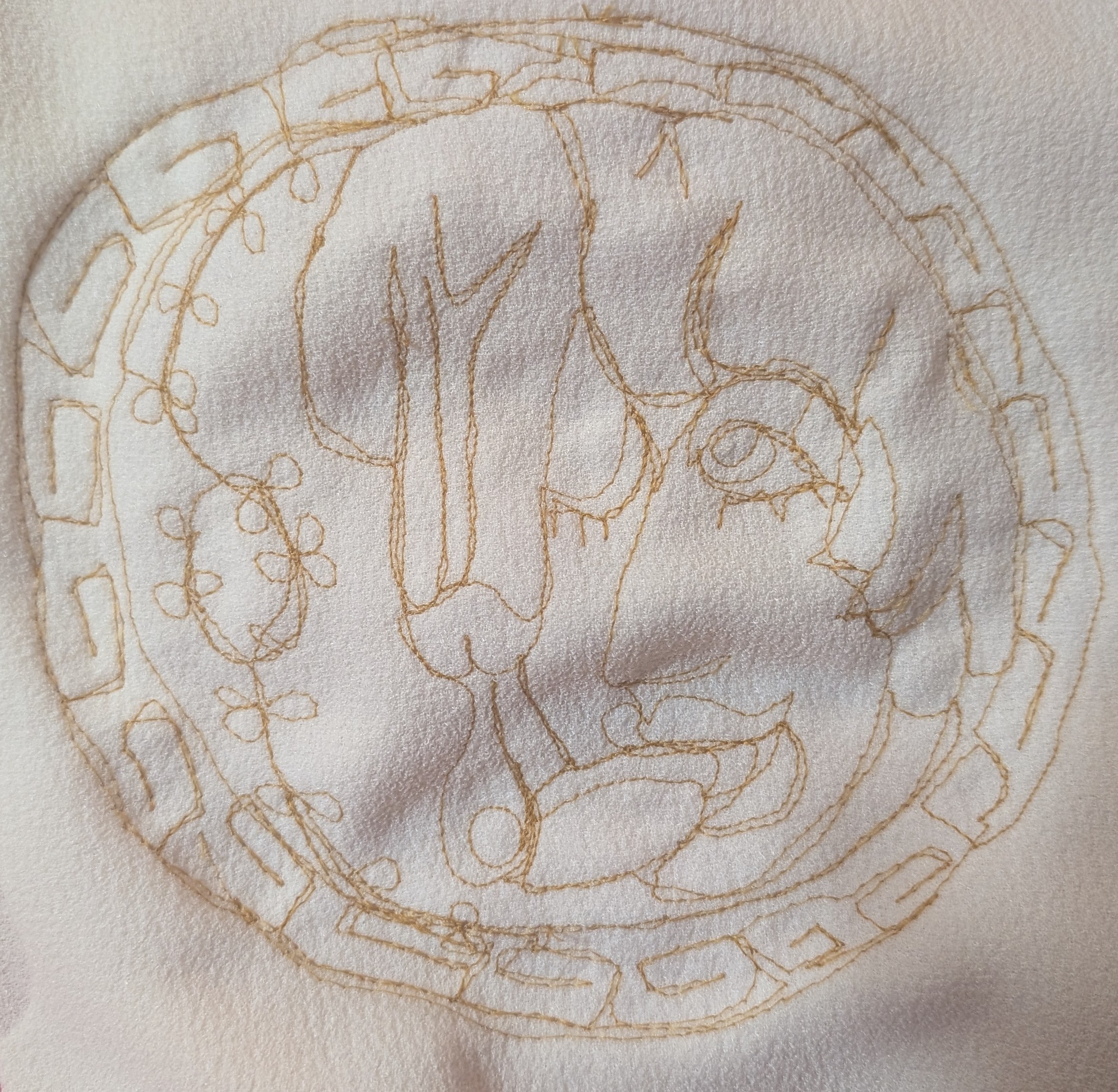 An embroidery of a young man, he is looking upwards and there is a penis cumming a large glob of cum onto his tongue
